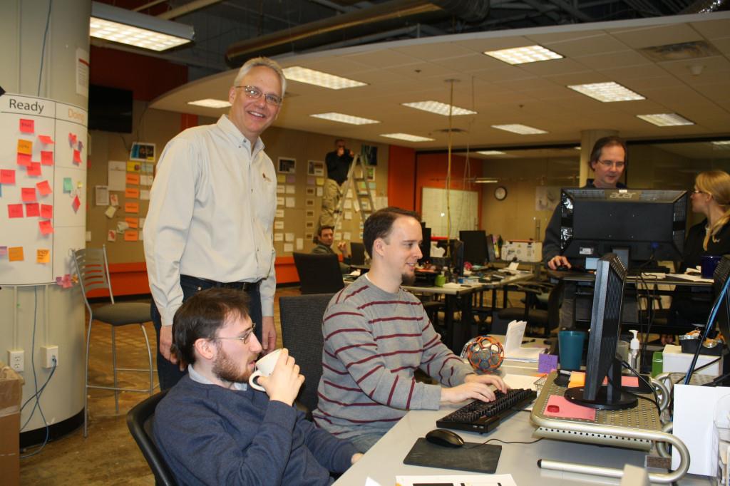 Menlo Innovations CEO Richard Sheridan talks with programmers at paired work stations. Photo by J.D. Booth
