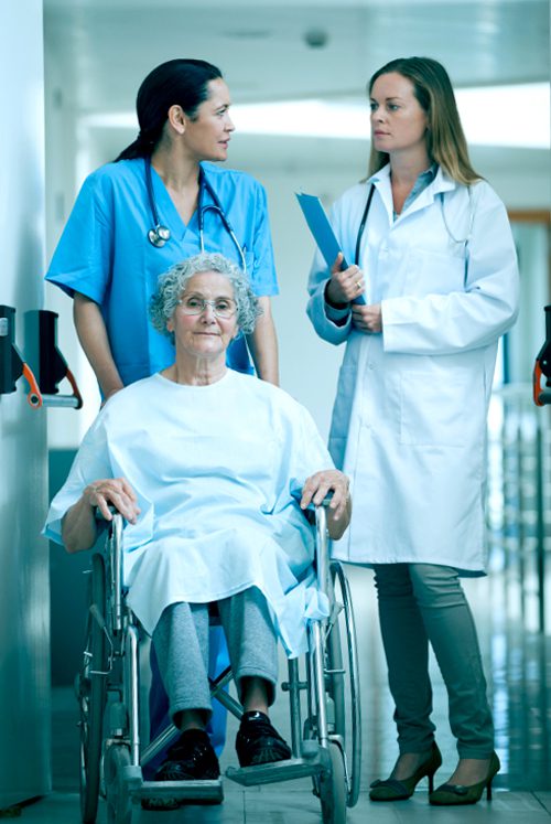 Nurse wheeling a senior patient patient in a hallway in a hospital