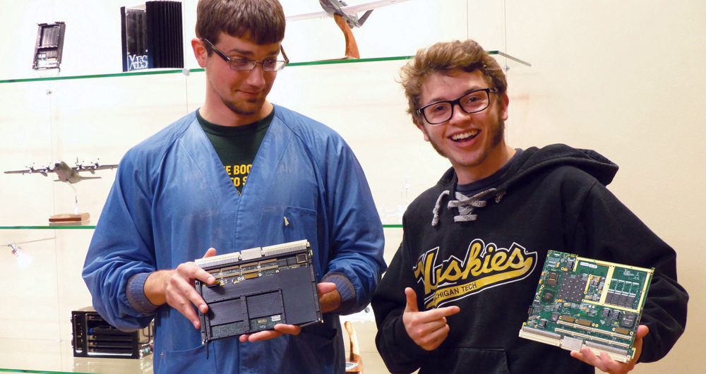Michigan Tech student Tayler Sly, right, worked in a co-op at Extreme Engineering Solutions, designing and testing computers for aerospace applications. Sly and a fellow co-op student show off computers they designed.