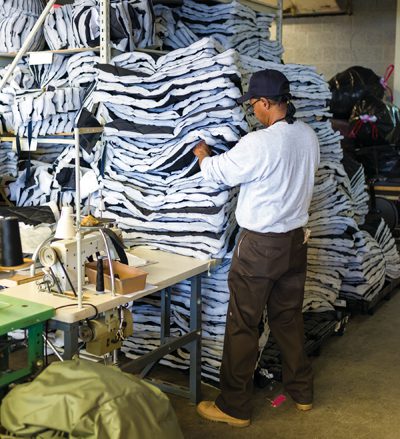 Reginald Hicks works with coat fabric. Since its founding in 2011, about 10,000 coats have been made.