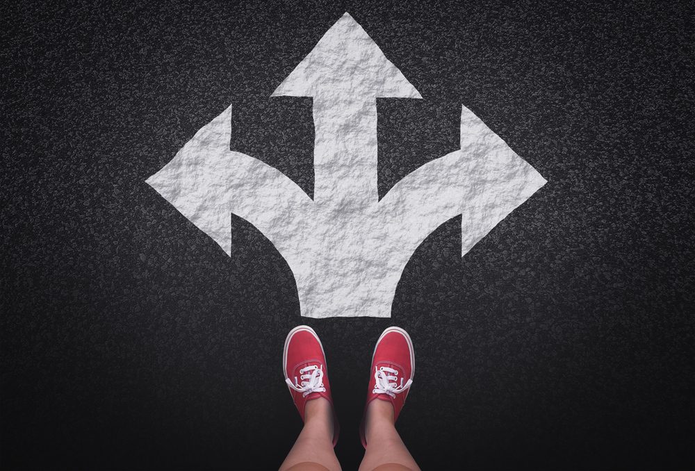 At a crossroads - Decisions and choices concept with large arrow