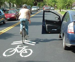 Passing cyclists are encouraged to give opening car doors a wide berth. Photo by Greater Grand Rapids Bicycle Coalition