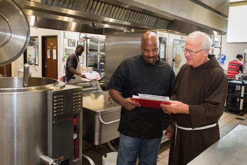 Capuchin Soup Kitchen Chef Jay Brown (left) and Brother Jerry Smith go over the day's menu near the new kitchen equipment donated through a makeover by DTE Energy and DNV GL.