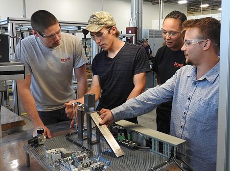 From left, Matthew Frick, Jesse Kirkland, Kelsey Erne and Matt Jaisle are part of the first class of MAT2 students to graduate in July. Now full-time at Brose North America, they’re pictured here at Brose’s prototype and test facility in Auburn Hills while training for their German-American Chamber of Commerce certification test. Photo by Brose