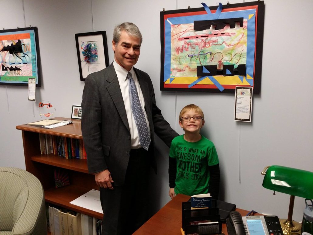 Will Matheson, a first-grader and artist from Walled Lake, stopped by Oakland Schools to visit his masterpiece, hanging on the wall of Assistant Superintendent of Educational Services Dr. Mike Yocum's office. Dr. Yocum hangs Oakland County students' art in his office as a way to stay connected to students and the classroom. 