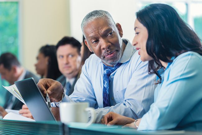 Senior businessman talking with colleague at seminar