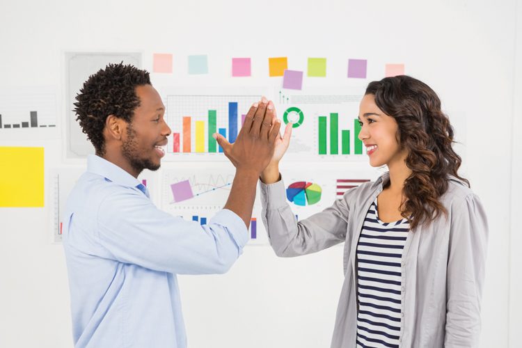 Young smiling business people clapping hands in the office