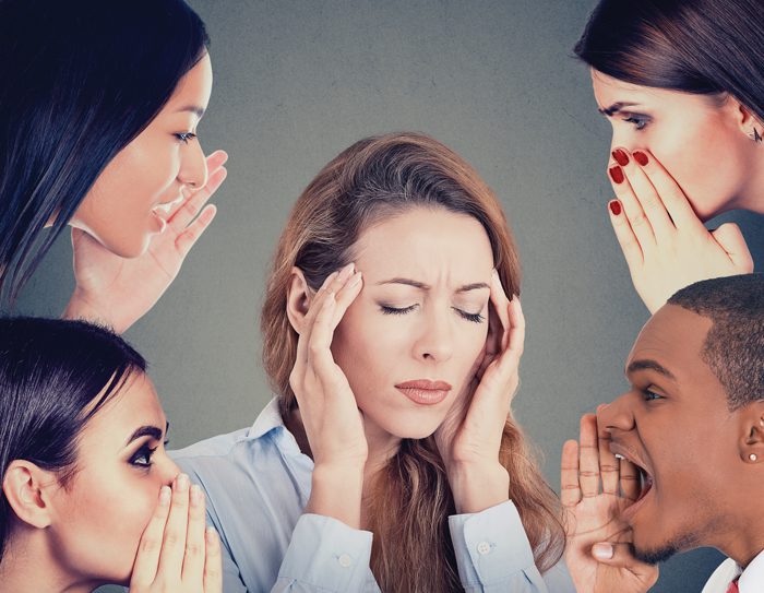 Group of people whispering gossip to a stressed woman suffering from headache